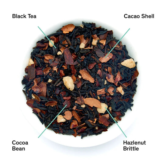 Close-up of hazelnut chocolate black tea blend with black tea, cacao shell, cocoa bean, and hazelnut brittle.