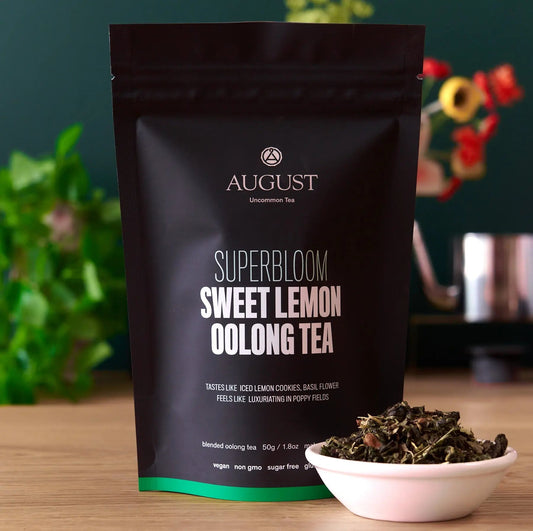 Superbloom Sweet Lemon Oolong Green Tea bag with loose tea leaves in a bowl, highlighting its citrus floral aroma.