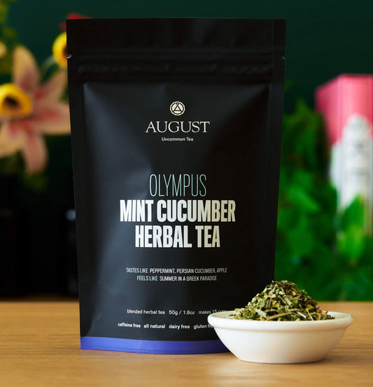 Olympus mint cucumber herbal tea bag next to a bowl of tea leaves, caffeine free mint cucumber herbal tea.