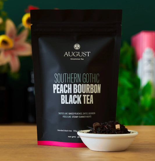 Southern Gothic Peach Bourbon Black Tea bag and loose tea on a table, showcasing baked peaches and caramel aroma.
