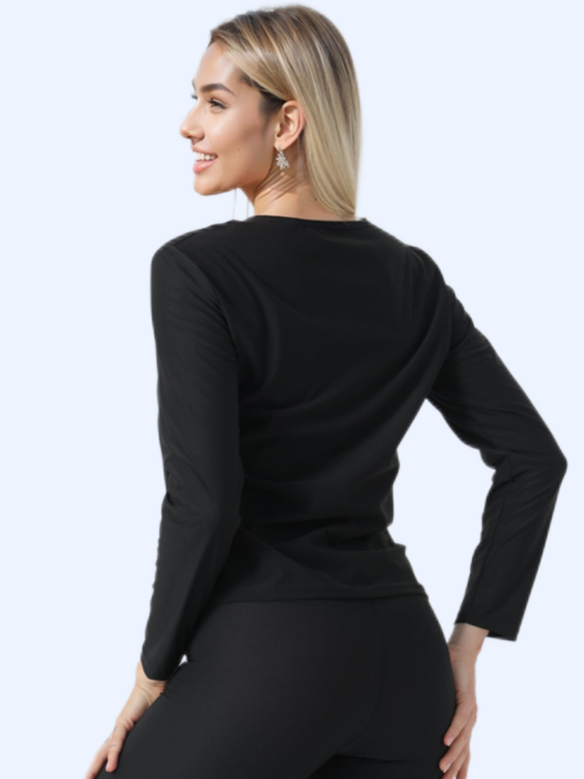 Woman wearing a sauna sweat suit women top, showcasing the back view of the long sleeve shirt in black.