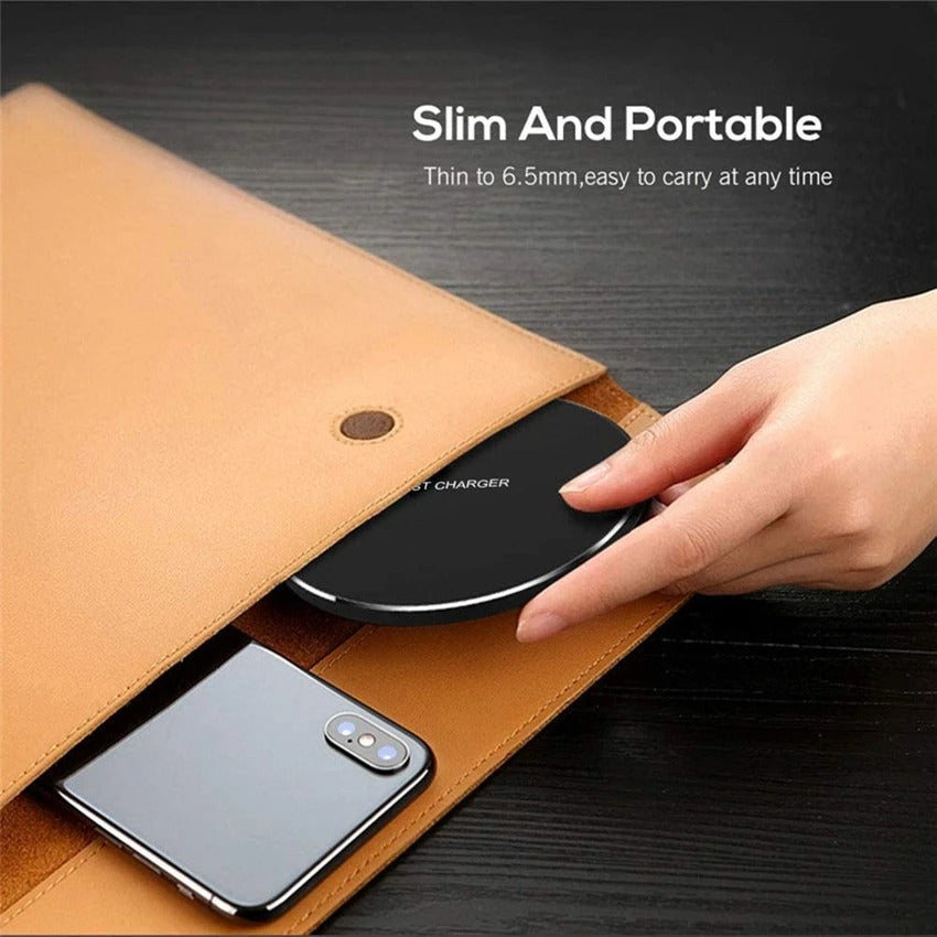 A hand placing a slim and portable fast wireless charger pad into a tan leather folder next to a smartphone.
