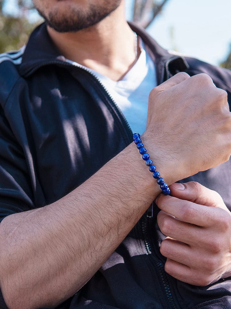 A man wearing a men's lapis lazuli beaded bracelet on his wrist, showcasing the deep blue beads.