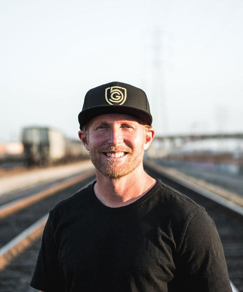 Man wearing a G5 Flat Billed Snap Back Hat, showcasing street style on a railway track.