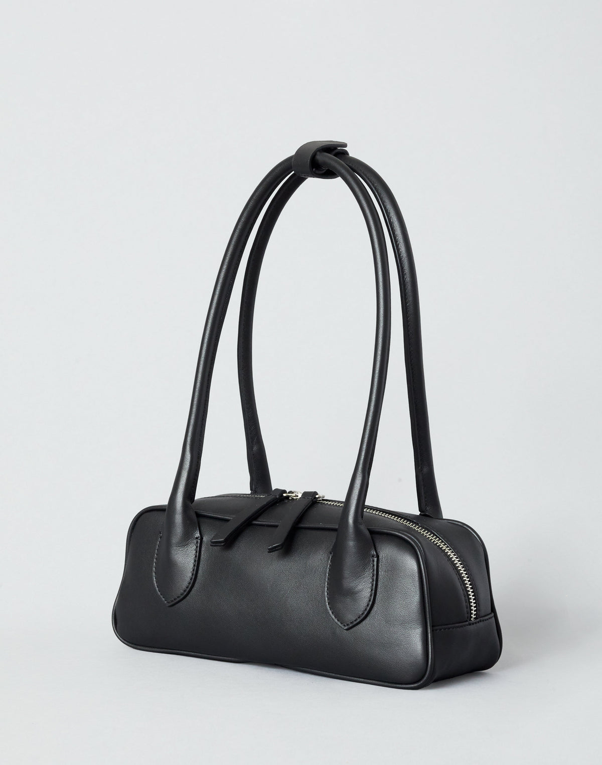 Mini La Strada structured leather baguette bag in black with dual handles and zipper closure.