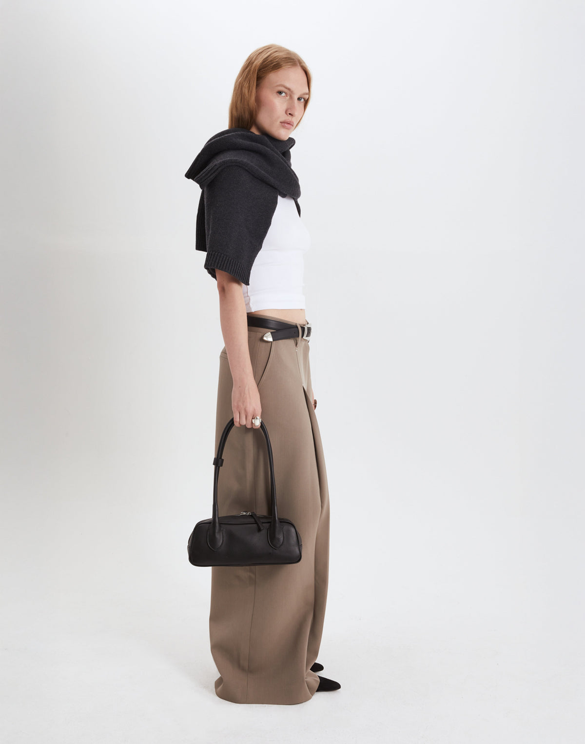 Woman wearing a chic outfit, holding a structured leather baguette bag for a stylish look.