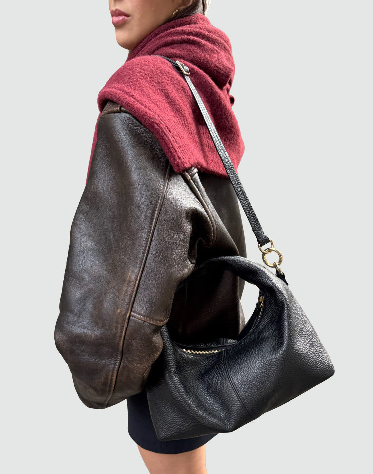 Model showcasing the Mini Everyday Shoulder Bag in black leather with a stylish outfit and red scarf.