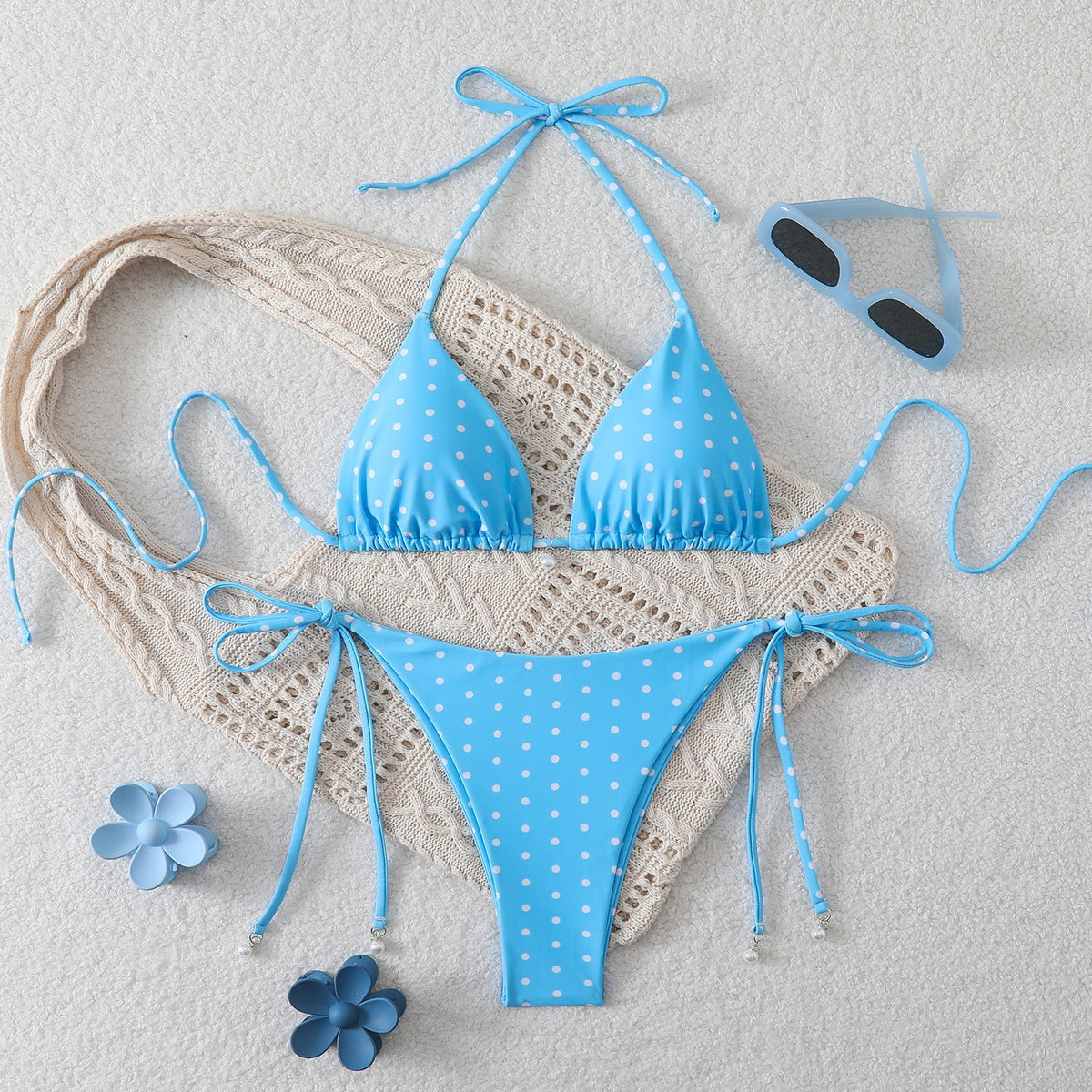 Sexy triangle separated strap multicolor polka dot bikini swimsuit in lake blue with floral accents on a soft surface.