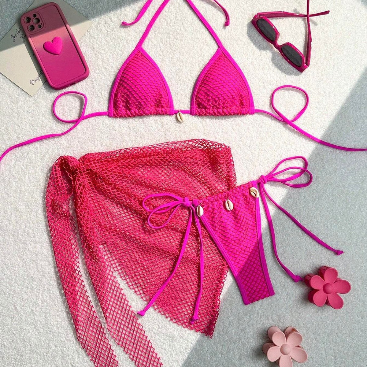 Three piece bikini swimsuit for women displayed in pink color with stylish accessories on a light background.