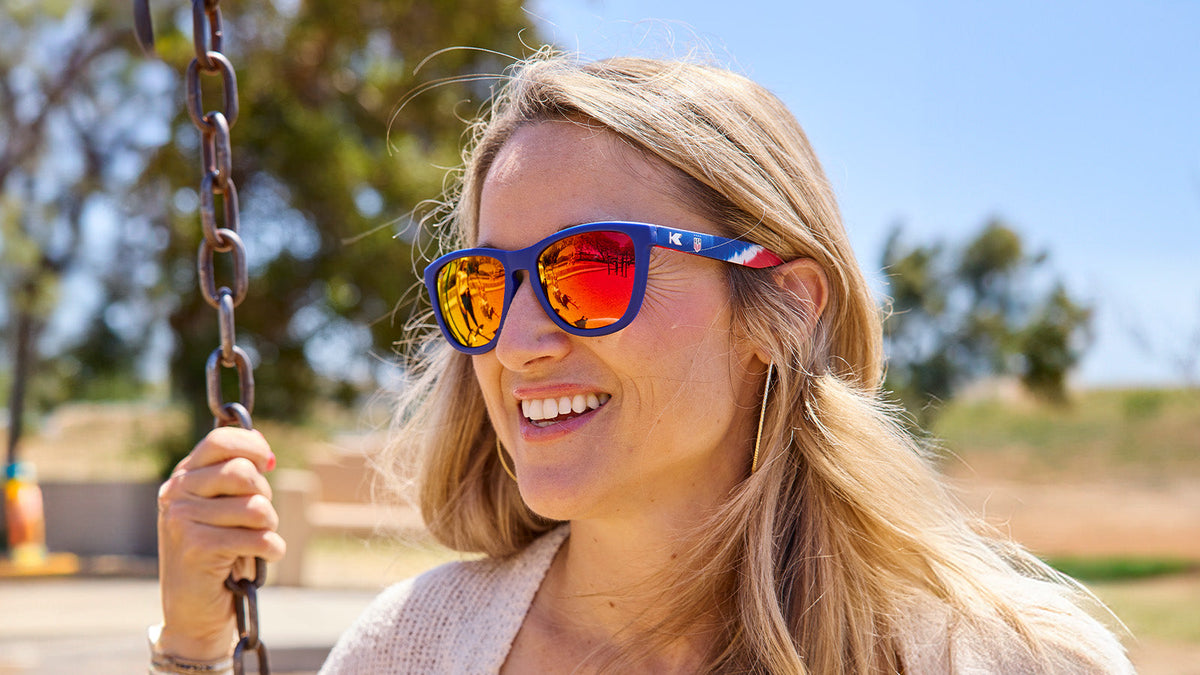 U.S. Soccer 2024 Knockaround Sunglasses worn by a woman on a swing with a sunny background.