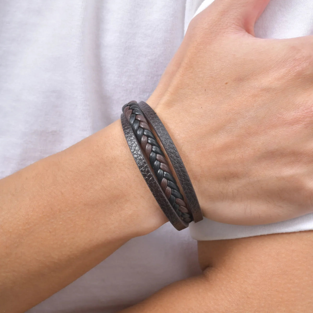 Close-up of a man wearing a multi-layer mens braided leather bracelet in black and brown handmade PU leather.