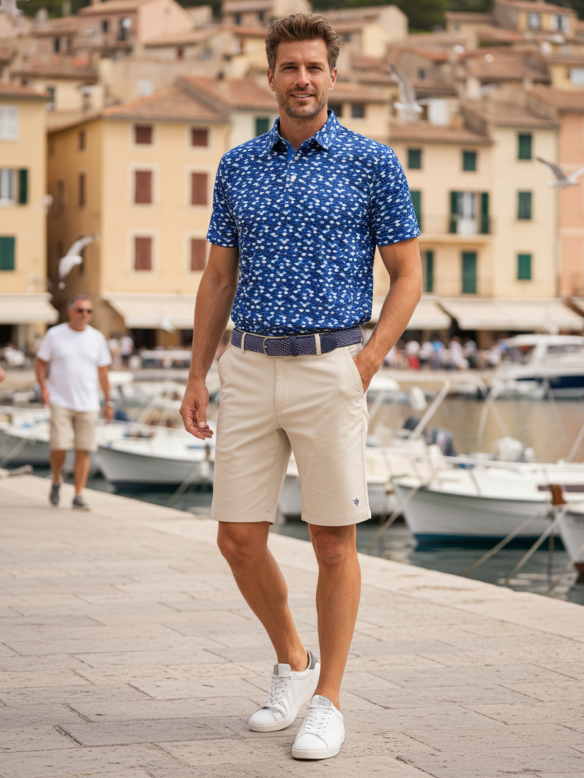 Man wearing a lightweight navy performance polo with beige shorts by the marina.