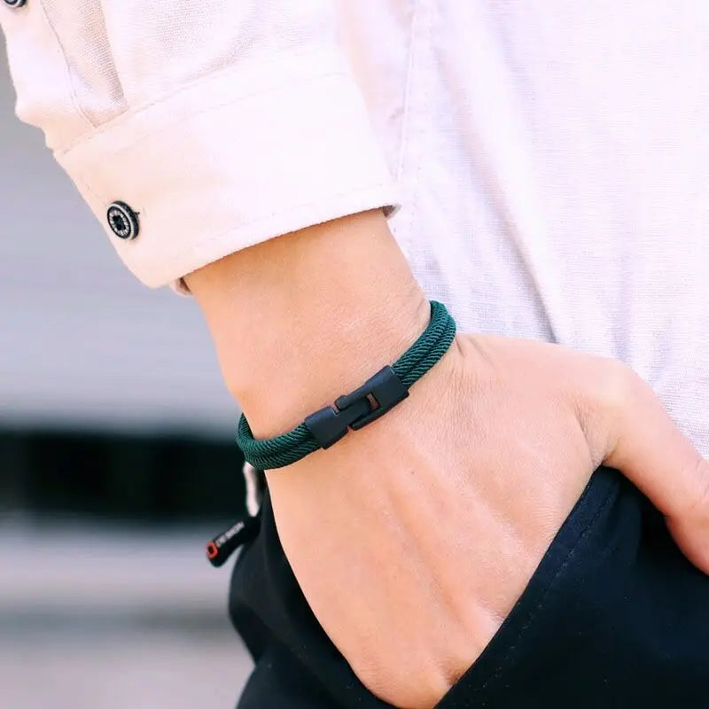 A man wearing a green men's double layer rope bracelet with a black clasp, styled with a white shirt and hand in pocket.