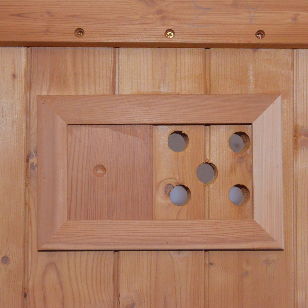 traditional cylindrical sauna wooden panel with framed openings and holes for ventilation