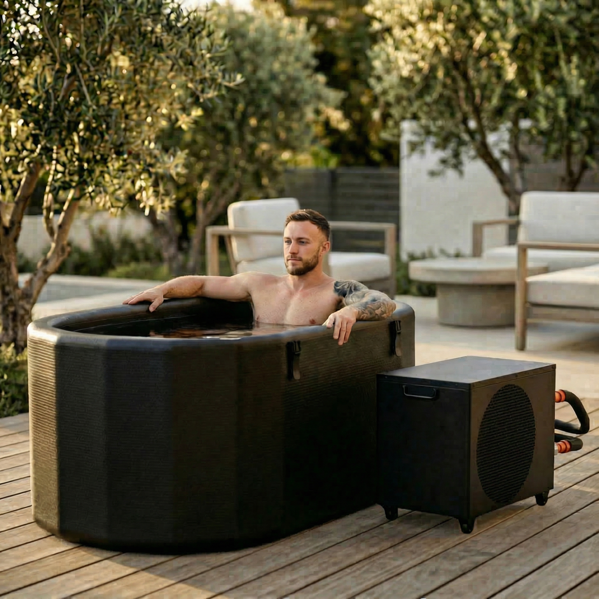 Man relaxing in the Nicebeam Cryo Pro System inflatable cold plunge tub on an outdoor wooden deck.